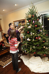 Familie schmückt Weihnachtsbaum zu Hause - CAVF36264