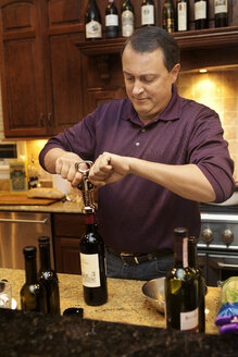 Mann öffnet Wein in der Küche - CAVF36267