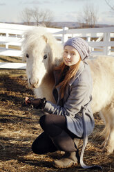 Porträt eines Teenagers mit weißem Pony auf einem Feld - CAVF36276