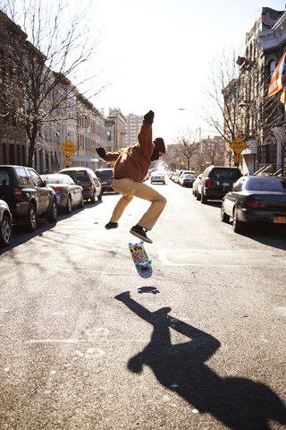 Mann skateboarding auf der Straße gegen den klaren Himmel, lizenzfreies Stockfoto