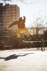 Man performing stunt with skateboard on city street - CAVF36302
