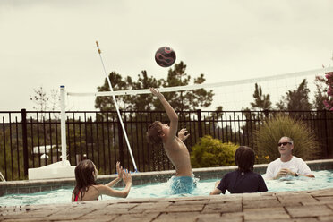 Glückliche Familie spielt Volleyball im Pool - CAVF36318