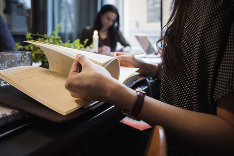 Midsection of woman turning pages sitting at table in creative office stock photo