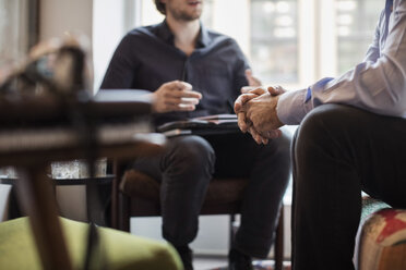 Mittelteil von Geschäftsleuten, die im Büro sitzend diskutieren - MASF03009