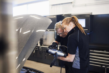 Mechaniker nutzen Technologie bei der Untersuchung von Autos in der Werkstatt - MASF03015