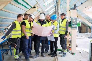 Manager, der mit Arbeitern auf einer Baustelle steht und Baupläne liest - MASF03022