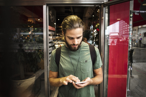 Man using smart phone against restaurant in city stock photo