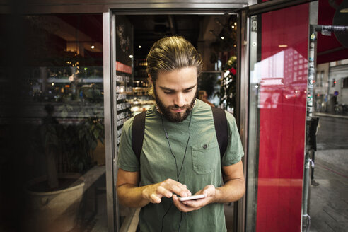 Mann mit Smartphone gegen Restaurant in der Stadt - MASF03040