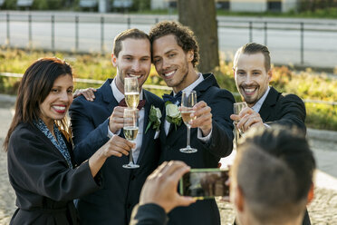 Glückliche Freunde mit Sektflöten posieren für ein Foto während der Hochzeitszeremonie - MASF03061