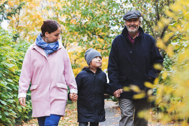 Glücklicher älterer Mann, der mit Urenkel und Tochter im Herbst im Park spazieren geht - MASF03071