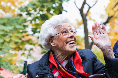 Glückliche ältere Frau, die im Herbst im Park gestikuliert und wegschaut, lizenzfreies Stockfoto