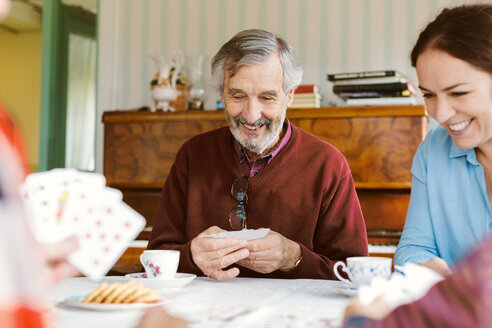 Happy senior man playing cards with family at home - MASF03076