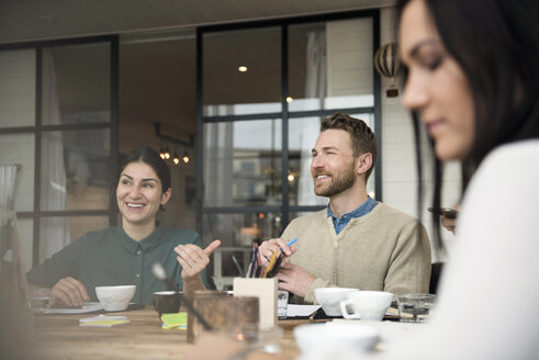 Glückliche Geschäftsleute, die sich bei einem Kaffee am Tisch während einer Besprechung im Büro unterhalten - MASF03080