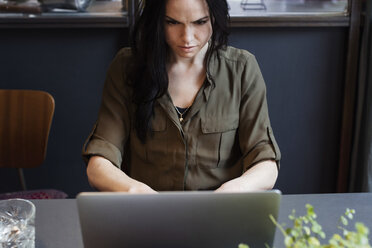 Hoher Blickwinkel der ernsten Geschäftsfrau, die einen Laptop benutzt, während sie am Tisch sitzt - MASF03088