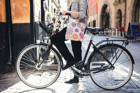Low section of woman standing with bicycle on cobbled street stock photo