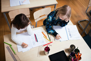 High angle view of schoolgirls studying at desk in school - MASF03098