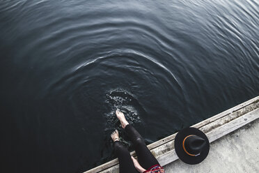 Niedriger Ausschnitt einer Frau, die auf einem Pier am Meer sitzt - CAVF36494