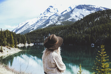 Rear view of woman in fedora hat looking at view by Lake Minnewanka - CAVF36515