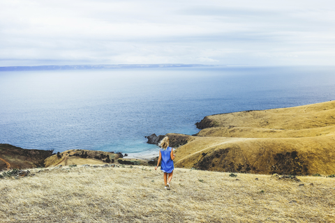 Hohe Winkel Ansicht der Frau zu Fuß am Blowhole Beach gegen Meer und Himmel, lizenzfreies Stockfoto
