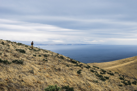 Wanderer am Berg steil gegen Meer und bewölkten Himmel, lizenzfreies Stockfoto