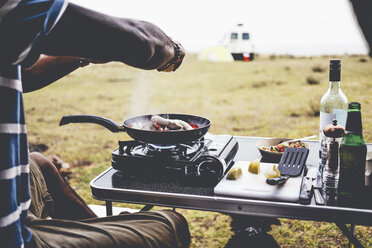 Ausgeschnittenes Bild eines Mannes, der auf einem Campingkocher Essen zubereitet - CAVF36541