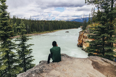 Mann betrachtet die Aussicht, während er auf einer Klippe im Jasper National Park sitzt - CAVF36564