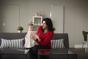 Mutter spielt mit Baby Tochter auf Sofa zu Hause - CAVF36607