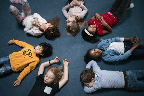 Direkt über der Aufnahme von Schulkindern, die in einem Klassenzimmer auf dem Boden liegen - MASF03141