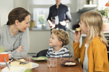 Family eating breakfast at dining table in living room - MASF03145