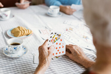 Cropped image of senior woman playing cards with family at table - MASF03165