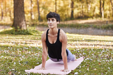 Mid adult woman in forest practicing yoga, cobra pose - SHOF00004
