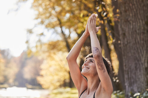 Lächelnde erwachsene Frau im Wald, die Yoga praktiziert - SHOF00013