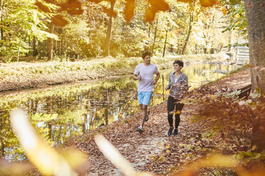 Pärchen joggt auf herbstlichem Waldweg - SHOF00017