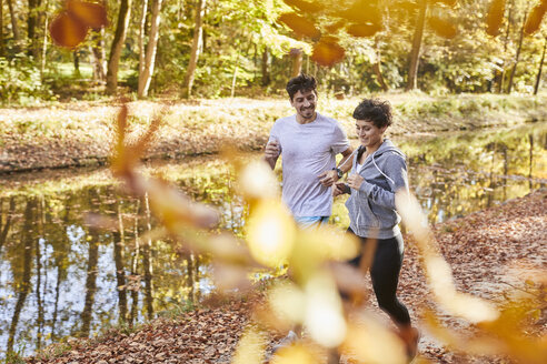 Pärchen joggt auf herbstlichem Waldweg - SHOF00018