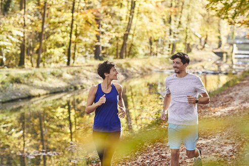 Pärchen joggt auf herbstlichem Waldweg - SHOF00026