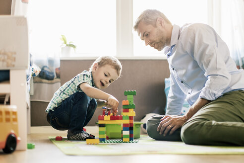 Vater und Sohn spielen mit Bauklötzen, während sie zu Hause sitzen - MASF03175