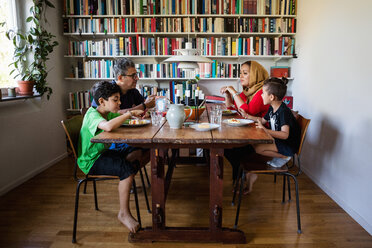 Family having meal at table by bookshelf - MASF03179