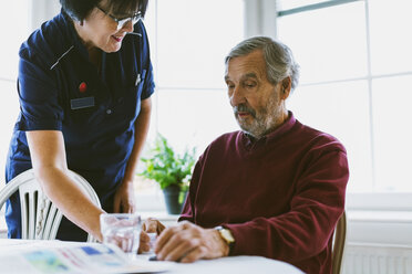 Female caretaker giving medicine to senior man at home - MASF03188