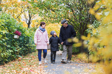 Full length of boy walking with great grandfather and mother in park during autumn - MASF03189