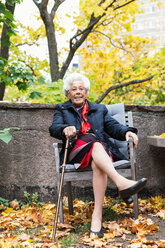 Ganzes Porträt einer glücklichen älteren Frau, die auf einem Stuhl im Park sitzt - MASF03190