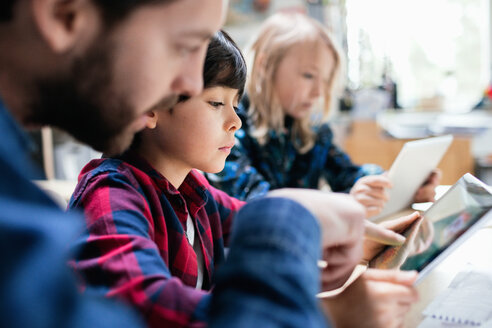 Nahaufnahme eines Lehrers, der den Schülern erklärt, wie man ein digitales Tablet am Schreibtisch benutzt - MASF03210