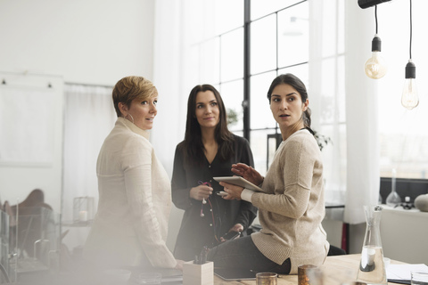 Geschäftsfrauen diskutieren, während sie im Büro stehen, lizenzfreies Stockfoto