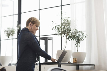 Geschäftsfrau hört Musik über Laptop am Tisch im Büro - MASF03233