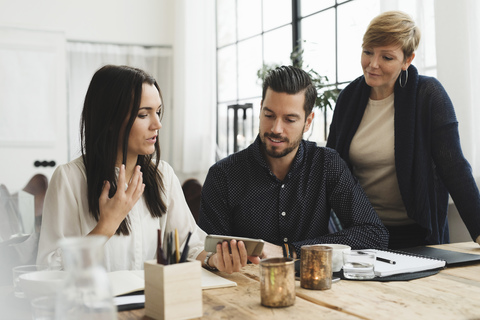 Business colleagues looking at smart phone held by woman during meeting stock photo