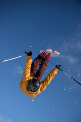 Low angle view of man performing stunt while skiing against clear blue sky - CAVF36646