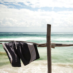 Badehose zum Trocknen auf einem Holzgeländer am Meer - CAVF36688