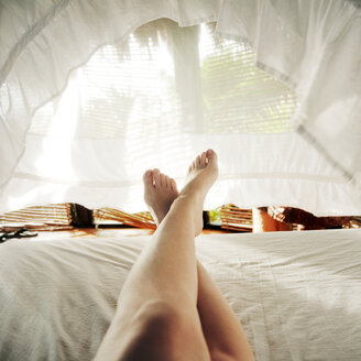 Ausgeschnittenes Bild einer Frau, die sich auf dem Bett entspannt - CAVF36692