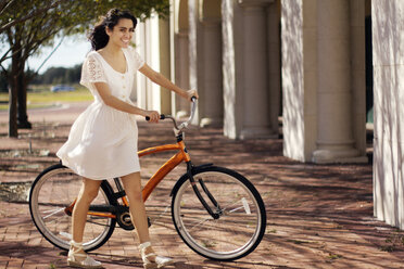 Glückliches Teenager-Mädchen mit Fahrrad an einem sonnigen Tag - CAVF36731