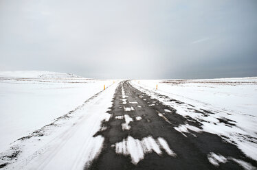 Scenic view of road amidst snow covered field - CAVF36751