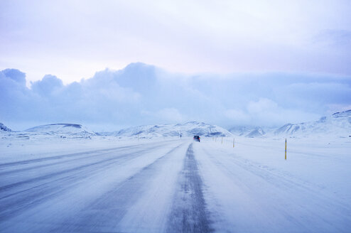 Auto auf schneebedeckter Straße gegen bewölkten Himmel - CAVF36753